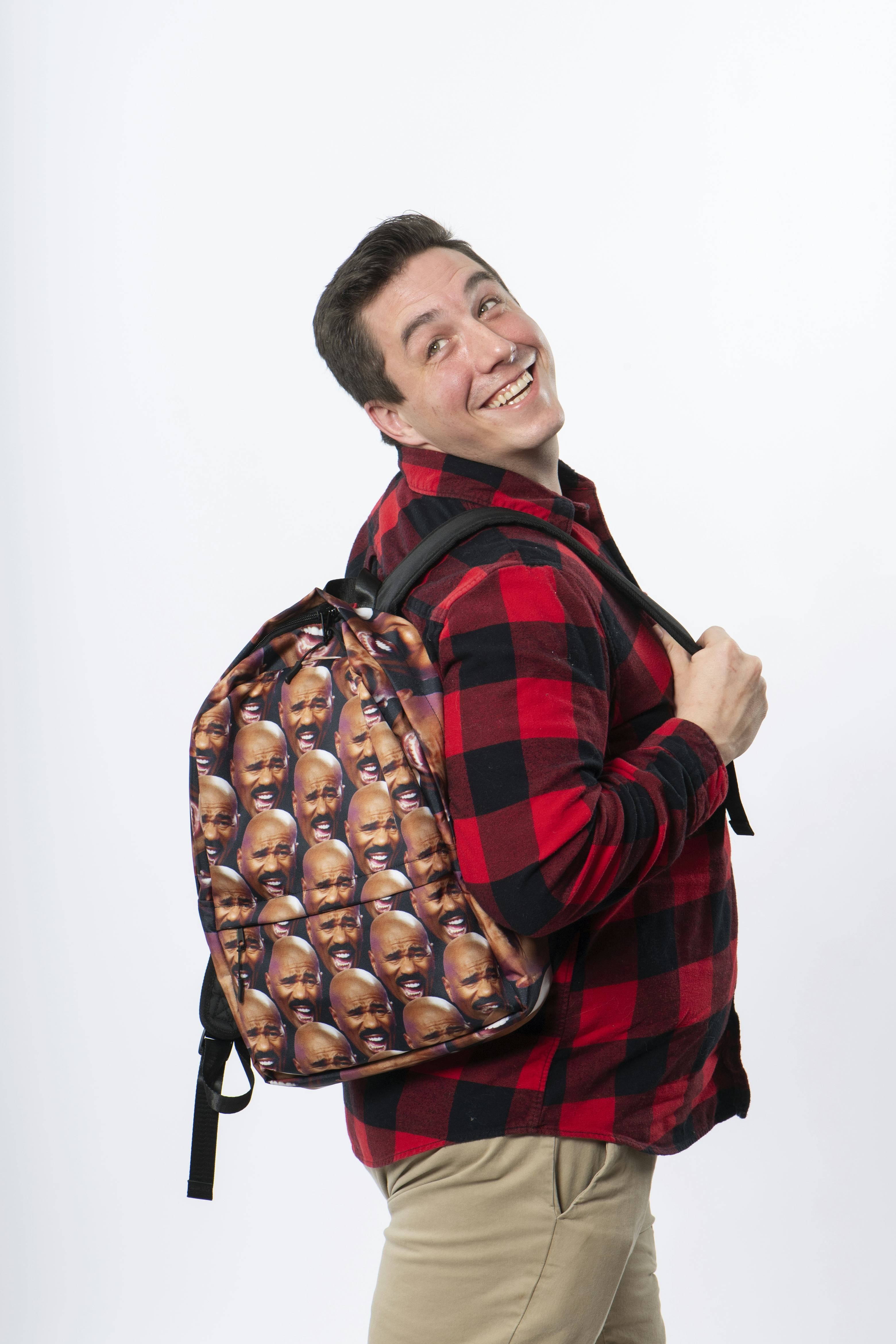 Person smiling while wearing a backpack with Steve Harvey’s laughing face printed in a pattern